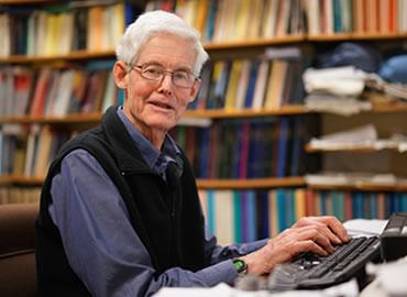 Stephen Cook at his desk typing on a laptop