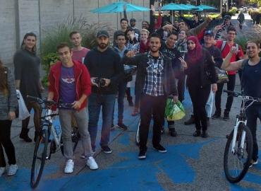 A group of young, smiling Syrian newcomers gathered outdoors for workshops led by U of T students