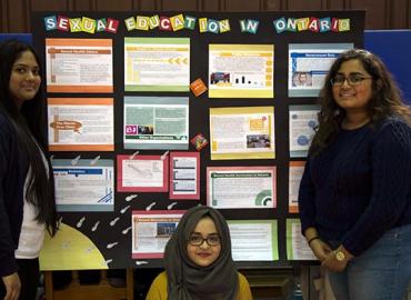 Three students standing in front of poster board titled &amp;quot;Sexual education in Ontario&amp;quot;