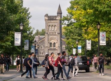 Students crossing a road in front of King&amp;#039;s College Circle. 