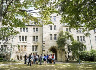 A group of students gather in front of St. Michael&amp;#039;s College on a beautiful summer day.