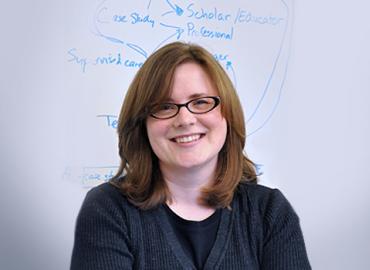 Alison Gibbs standing in-front of a white board.