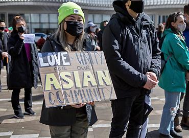 A women holding a sign that says - Love, unity for Asian community.