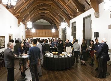 A large group of people gather under cathedral ceilings at Hart House for Backpack to Briefcase.