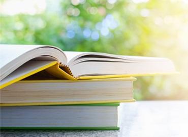 A stack og books in front of a sunny window with the light dancing