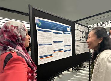 Two people standing in front of a poster board.