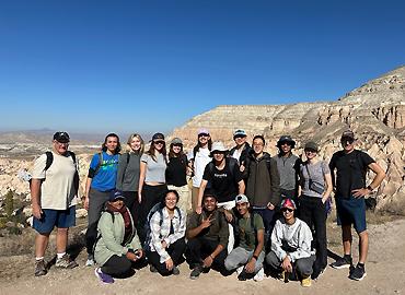 A group of students and instructors stand in the Rose Valley in Cappadocia, Türkiye on a beautiful sunny day.