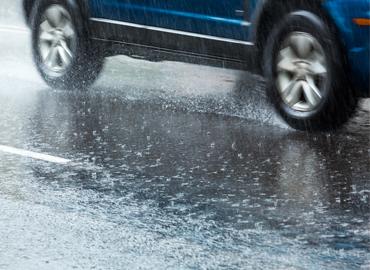 A side view of a car driving in the rain.