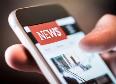 Close up of hands holding cellphone with NEWS page open.