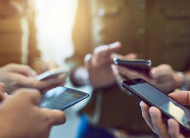 A close-up of a group of people&amp;#039;s hands, each holding a cell phone