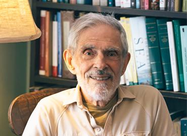 Chandler Davis sitting in a chair in a cozy-looking book-lined room