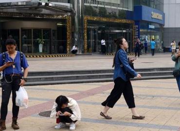A group of women looking at their mobile phones outside a mall in Beijing. 