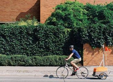 Second-year student Colin Arrowsmith bikes along Huron Street, pulling a device to measure greenhouse gas emissions on U of T’s St. George campus.