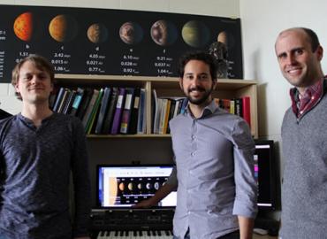 Andrew Santaguida, Matt Russo and Dan Tamayo standing in front of a poster of Saturn&amp;#039;s moons.
