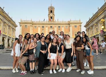 A group of students pose for a picture in front of an old building in Siena.
