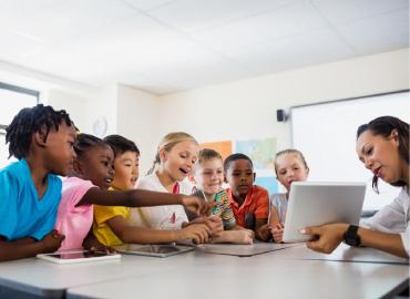 A group of children looking at an iPad with a teacher.