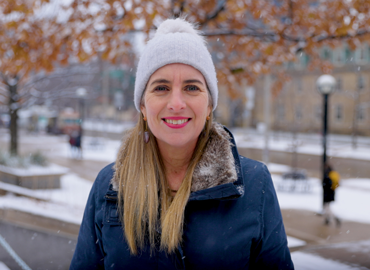 Dean Woodin stands in front of snowy Sidney Smith Hall wearing a beanie.