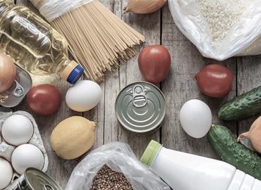 a table with canned food, pasta and vegetables on it