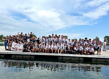 A large group of people pose for a picture in front of a lake.