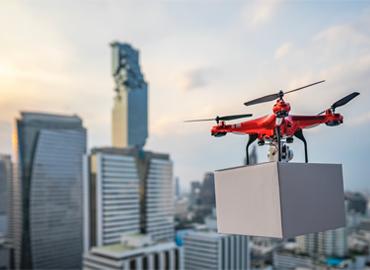A drone with a box flying over a city.