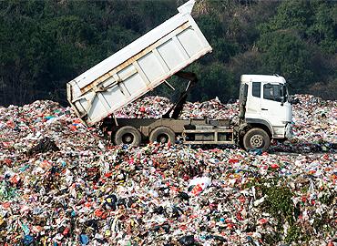 A truck dumping garbage into a landfill.