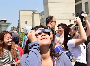 A group of people looking up at the sky with sunglasses.