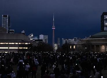 A group of people looking at the eclipse from the U of T Centre Campus lawn