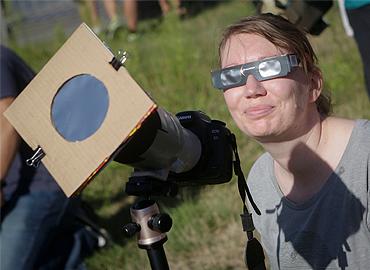 A person with black sunglasses on viewing an eclipse.