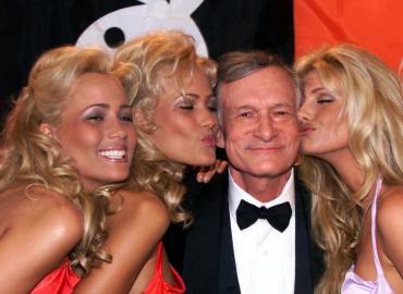 Playboy founder Hugh Hefner receives kisses from Playboy playmates