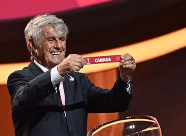 Former Serbian footballer Bora Milutinović holds the card showing the name of Canada during the draw 