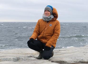 Frances Garrett on rock on a beach - cold day