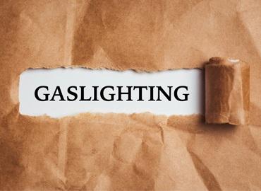 The word Gaslighting appearing behind torn brown paper