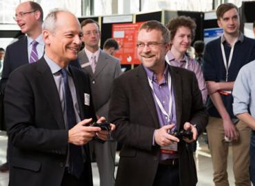 Students watch as Paul Gries (right) teams up with U of T President Meric Gertler to play a student-designed video game.