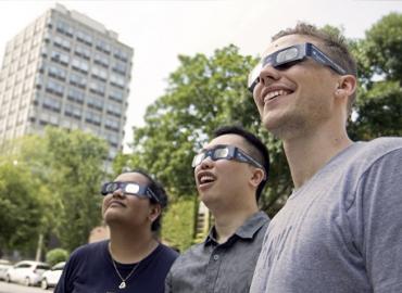 Three students wearing solar eclipse glasses