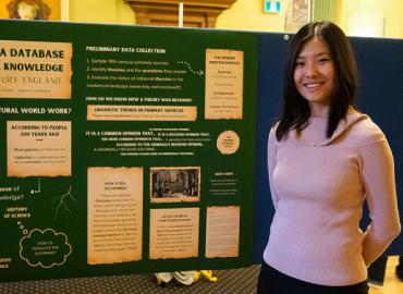 Grace Shan standing beside a presentation board with information about her research project.