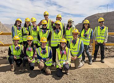 A group of students in yellow safety vests on top of a rocky outcropping