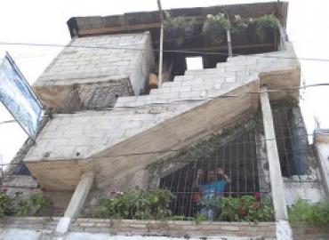 Run down building with person looking through bars