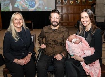 Two women and one man - one woman is holding a baby.