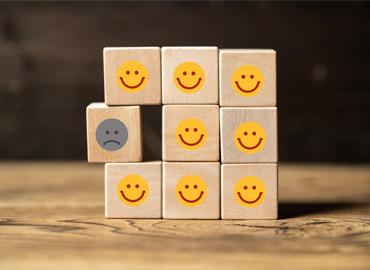 A group of wood blocks with frowning and happy face icons.