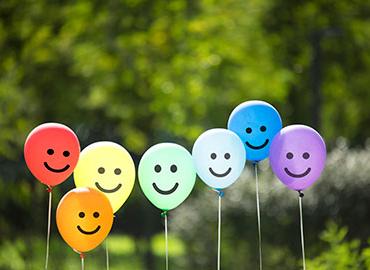 A group of colourful balloons with happy faces