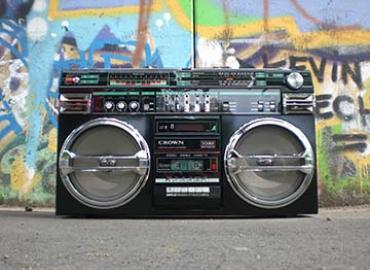 a old school beat box cassette player against a wall with graffitti
