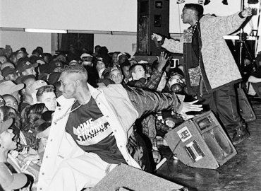 Black and white photo of two men performing on stage in front of a crowd of people.