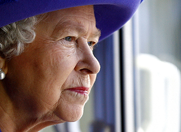 Her Majesty Queen Elizabeth II in a blue hat and beautiful earrings looking into the distance