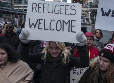 Group at a pro refugee rally holding welcome signs. 