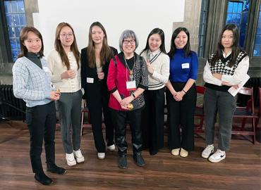 Evelyn Foo standing smiling with six people in a room.