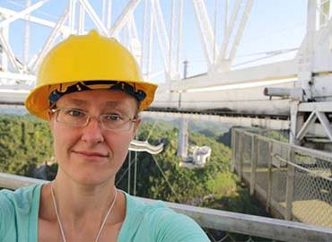 Jennifer West in a hardhat on a steel structure 