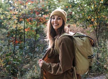 Jaime Grimm on a hike in a forest with a backpack 