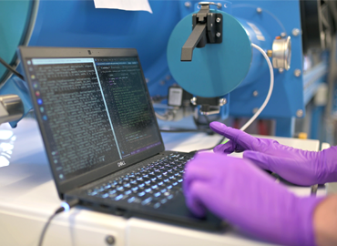 gloved hands on a laptop in a lab setting