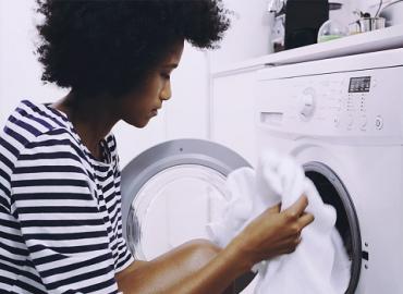 A woman putting clothes into a washing machine