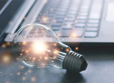 an illuminated lightbulb beside a laptop